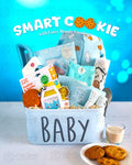 A baby gift basket labeled 'Smart Cookie' with various baby items like a onesie, recording journal, clothes hangers, hooded towel, and more, presented in a blue fabric basket.
