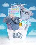 A baby gift set by Cutey Beauty Creations, featuring a gray elephant plush toy, a blue and gray elephant-themed blanket, a gray and blue onesie, a storybook, and a variety of baby essentials like wipes and bibs, all arranged in a white storage bin with a cloudy backdrop.